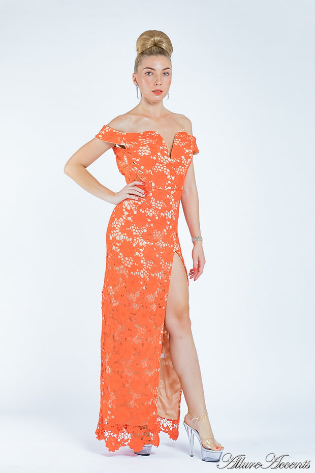 Woman wearing an orange off-the-shoulder lace dress with a front slit. 
