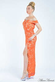 Woman wearing an orange off-the-shoulder lace dress with a front slit.