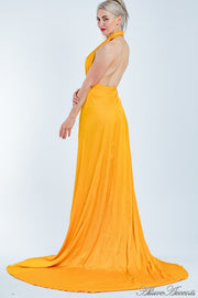 Woman wearing an orange silk satin, halter neck gown with a high leg slit.