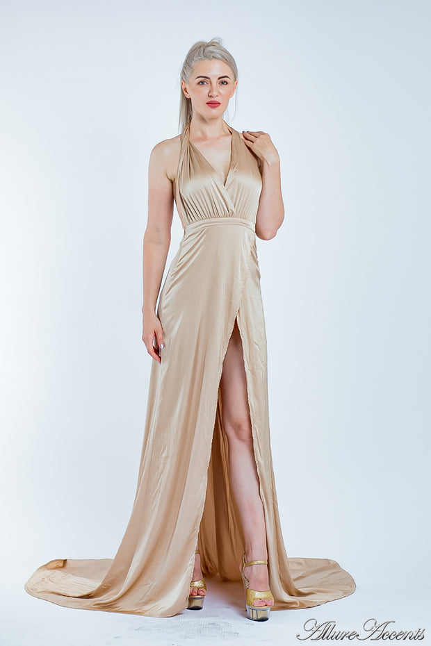 Woman wearing a champagne gold silk satin halter neck gown with a high leg slit.