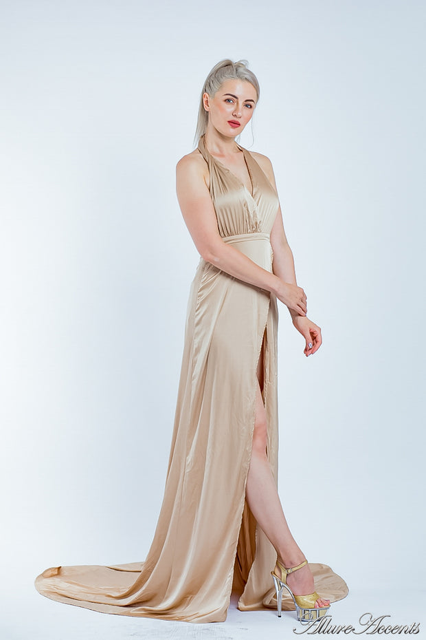 Woman wearing a champagne gold silk satin halter neck gown with a high leg slit.