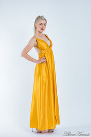 Woman wearing a gold long satin dress that has a deep v neckline.