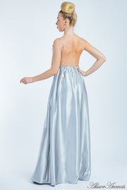 Woman wearing a silver long satin dress showing it has a low back.