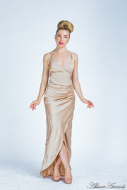 Woman wearing a long champagne gold colored silk dress with ruching.