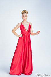 Woman wearing a red colored long satin dress that has a deep v neckline.
