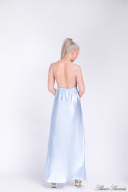 Woman wearing an icy blue long satin dress showing it has a low back.