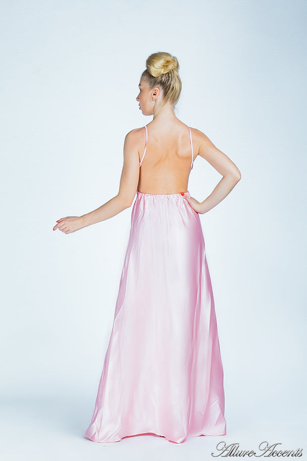 Woman wearing a blush pink long satin dress showing it has a low back.