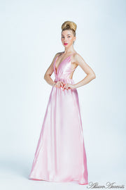 Woman wearing a blush pink long satin dress that has a deep v neckline.