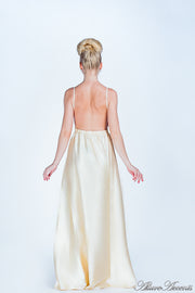 Woman wearing a carmel long satin dress showing it has a low back.
