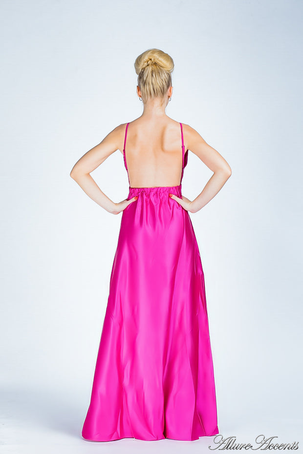Woman wearing a barbie pink long satin dress showing it has a low back.