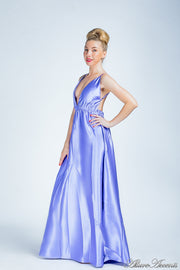 Woman wearing a periwinkle colored long satin dress that has a deep v neckline.