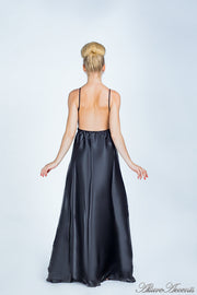 Woman wearing a black long satin dress showing it has a low back.
