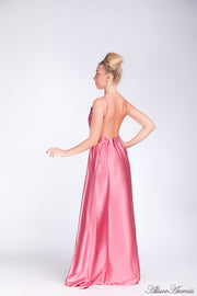 Woman wearing a pink long satin dress that has a deep v neckline.