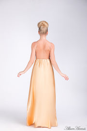 Woman wearing a champagne gold long satin dress showing it has a low back.
