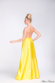 Woman wearing a yellow long satin dress that has a deep v neckline.