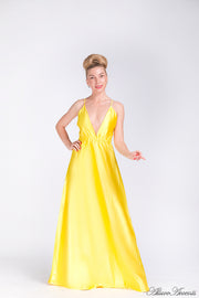 Woman wearing a yellow long satin dress that has a deep v neckline.