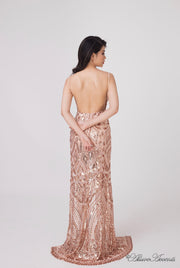 Woman showing the long champagne gold sequined dress is backless.