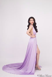 Woman wearing a lavender silk satin, halter neck gown with a high leg slit.