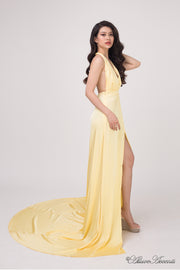 Woman wearing a yellow silk satin, halter neck gown with a high leg slit.