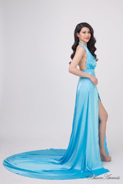 Woman wearing a baby blue silk satin, halter neck gown with a high leg slit.