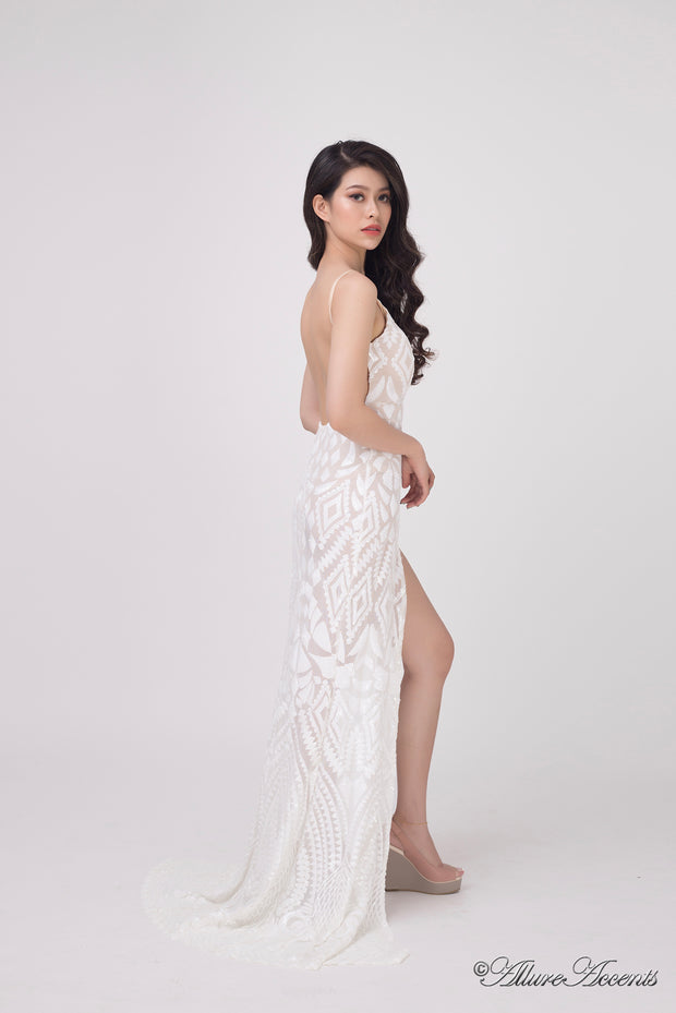 Woman wearing a long all white sequined dress with a high slit.