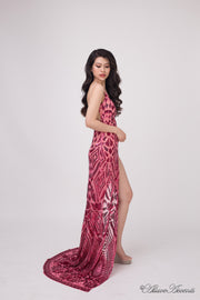 Woman wearing a long red sequined dress with a high leg slit.