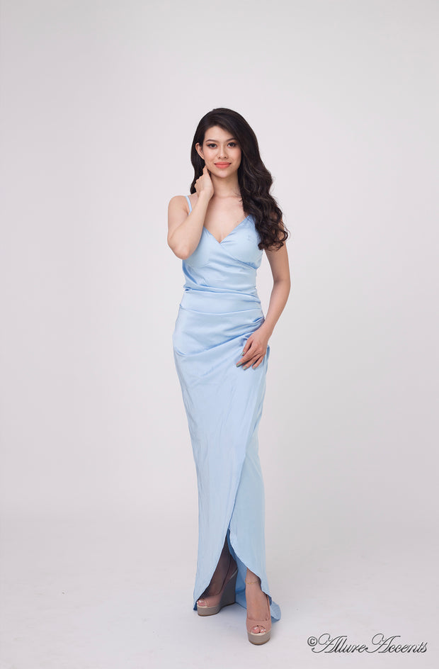 Woman wearing a long icy blue colored silk dress with ruching.