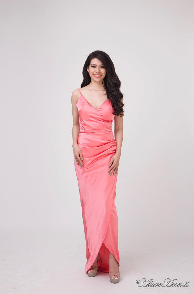 Woman wearing a long coral colored silk dress with ruching.