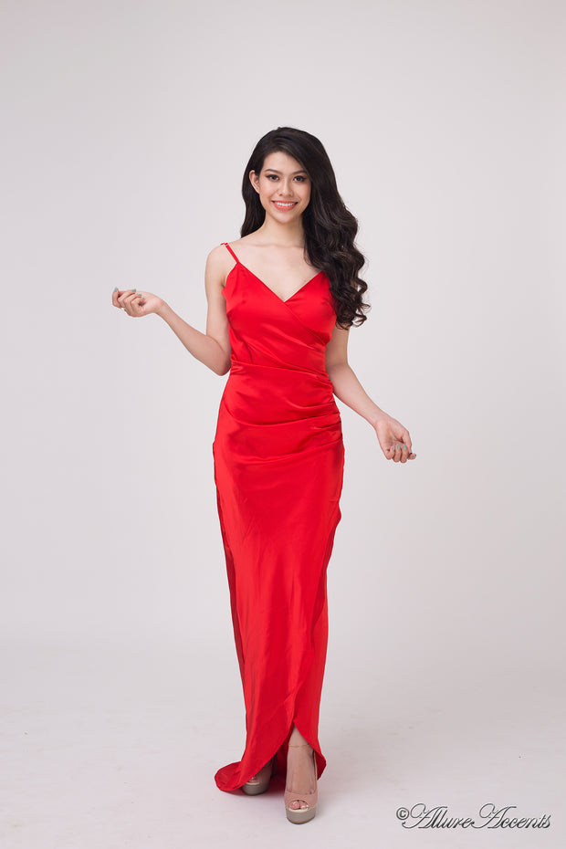 Woman wearing a long red colored silk dress with ruching.
