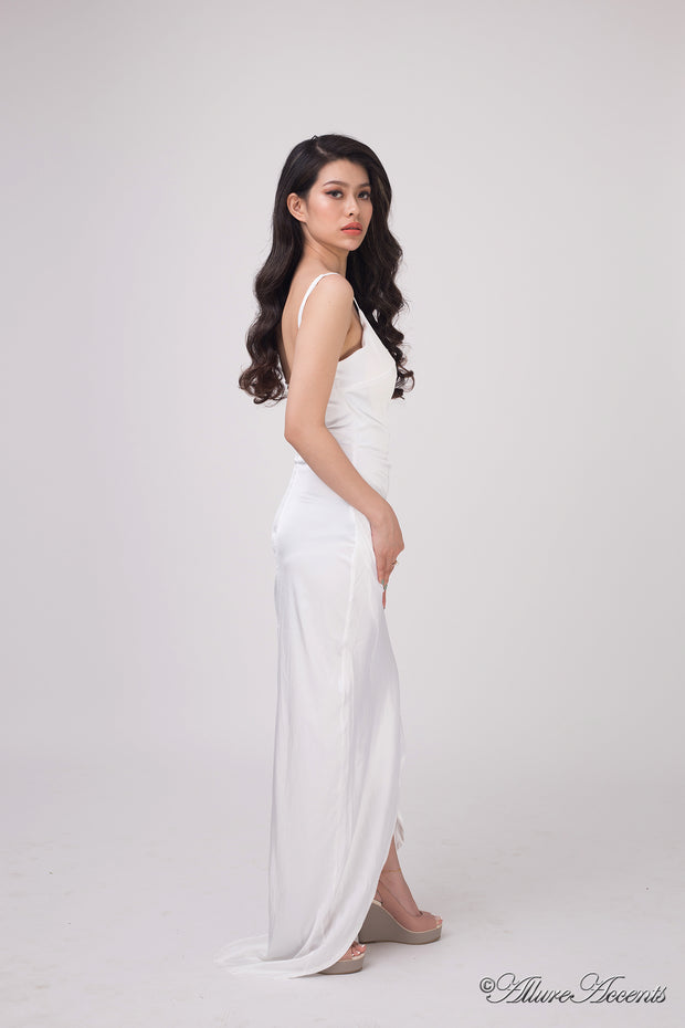Woman wearing a long white colored silk dress with ruching.