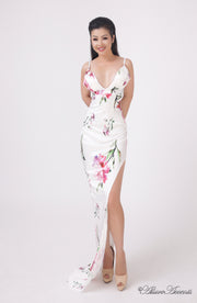 Woman wearing a white summer satin floral party maxi, low cut back and has sexy side slit 