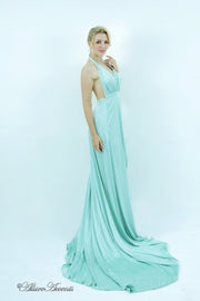 Woman wearing a mint colored silk satin, halter neck gown with a high leg slit.