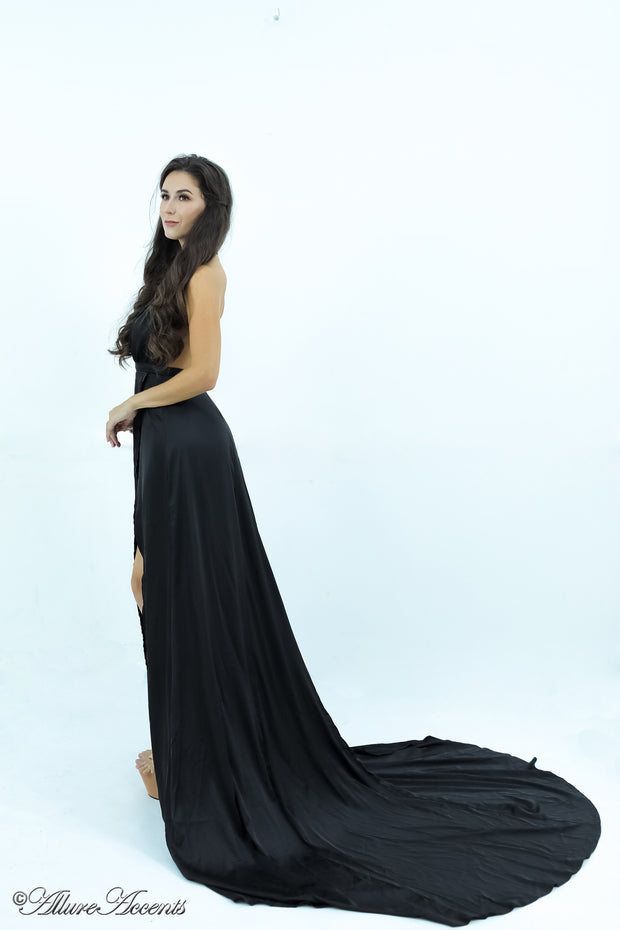 Woman wearing a black silk satin, halter neck gown with a high leg slit.