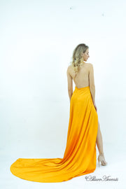 Woman wearing a yellow silk satin, halter neck gown with a high leg slit.