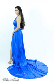 Woman wearing a royal blue silk satin halter neck gown with a high leg slit.