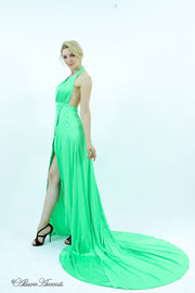 Woman wearing a lime green silk satin, halter neck gown with a high leg slit.