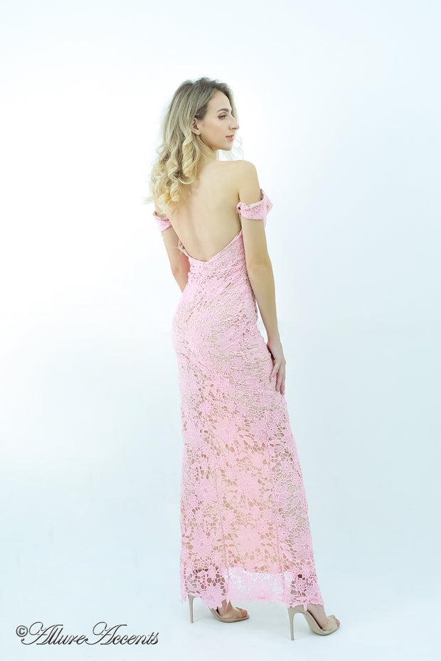 Woman wearing a baby pink off-the-shoulder lace dress with a front slit.
