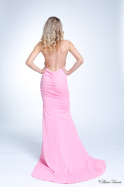 Woman showing her long baby pink gown is backless and has ruching on the butt. 