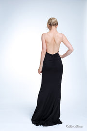 Woman showing her long black gown is backless and has ruching on the butt. 
