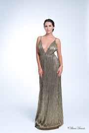 Woman wearing a gold colored maxi length slip dress with a deep v neck.