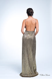 Woman wearing a gold long maxi length slip dress showing it has a low back cut.