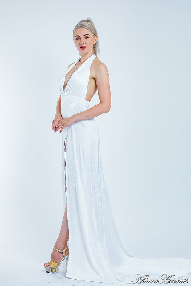 Woman wearing a white silk satin, halter neck gown with a high leg slit.