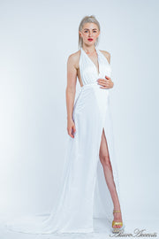 Woman wearing a white silk satin, halter neck gown with a high leg slit.