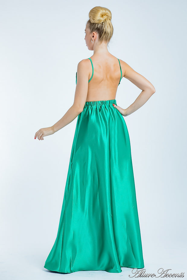 Woman wearing a jade green long satin dress that has a deep v neckline.