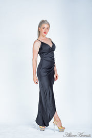 Woman wearing a long black colored silk dress with ruching.