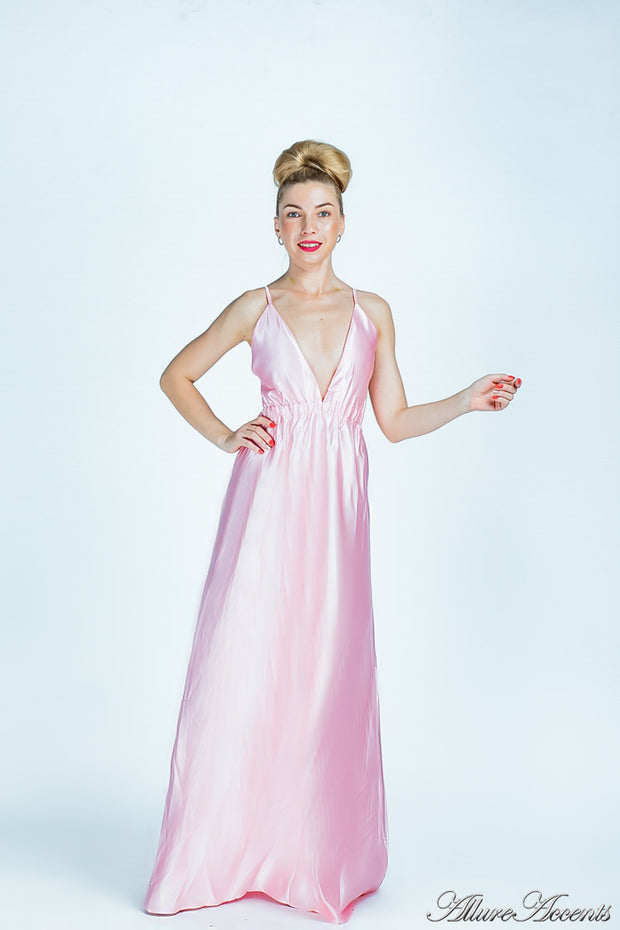 Woman wearing a blush pink long satin dress that has a deep v neckline.