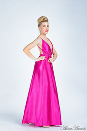 Woman wearing a barbie pink long satin dress that has a deep v neckline.