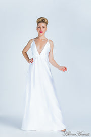 Woman wearing a white long satin dress that has a deep v neckline.