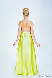 Woman wearing a lemon colored long satin dress that has a deep v neckline.