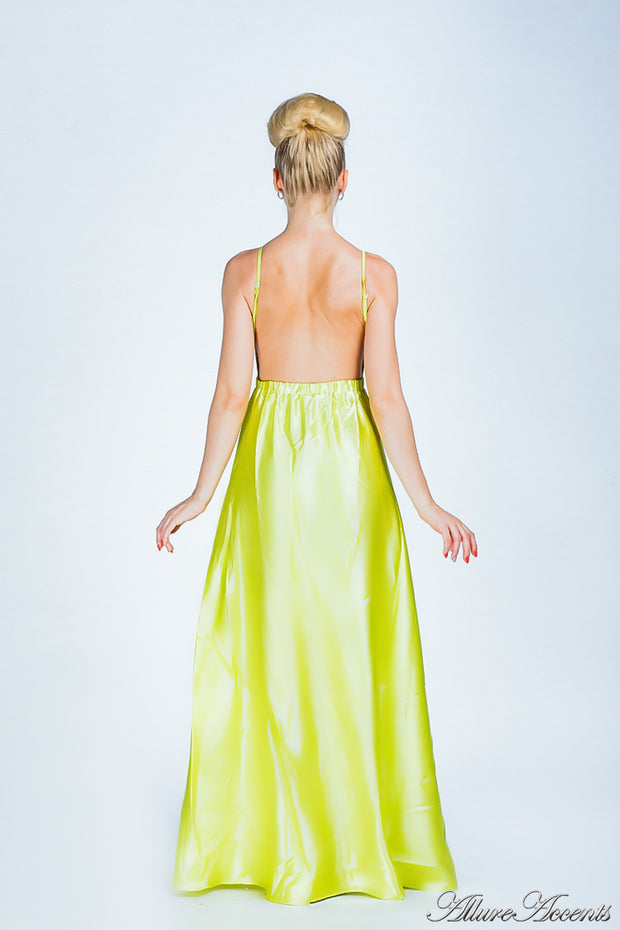 Woman wearing a lemon colored long satin dress that has a deep v neckline.